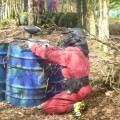 Paintballer hiding behind drum