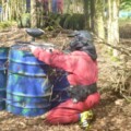 Paintballer hiding behind drum